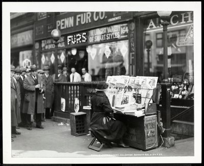 Blind news dealer, Aaron Weintraub, at his stand at the south east corner of 7th Avenue and 32nd Street, New York, 1926 by Byron Company